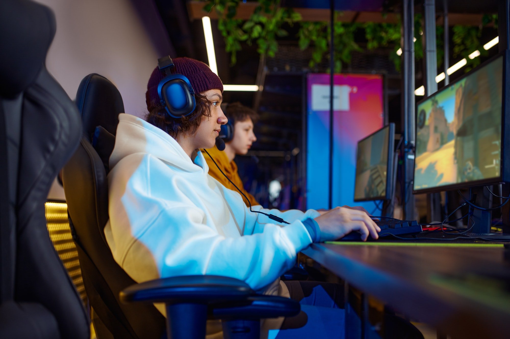 Two young gamers in headsets play in video game club