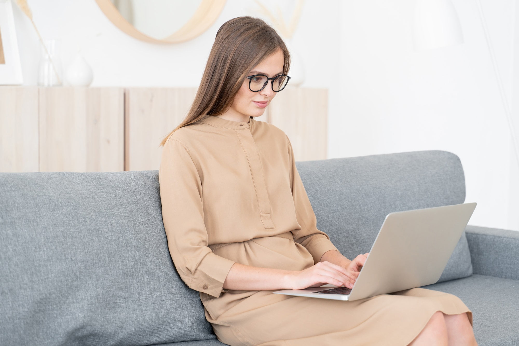 Young business woman sitting on sofa with open laptop, working from home