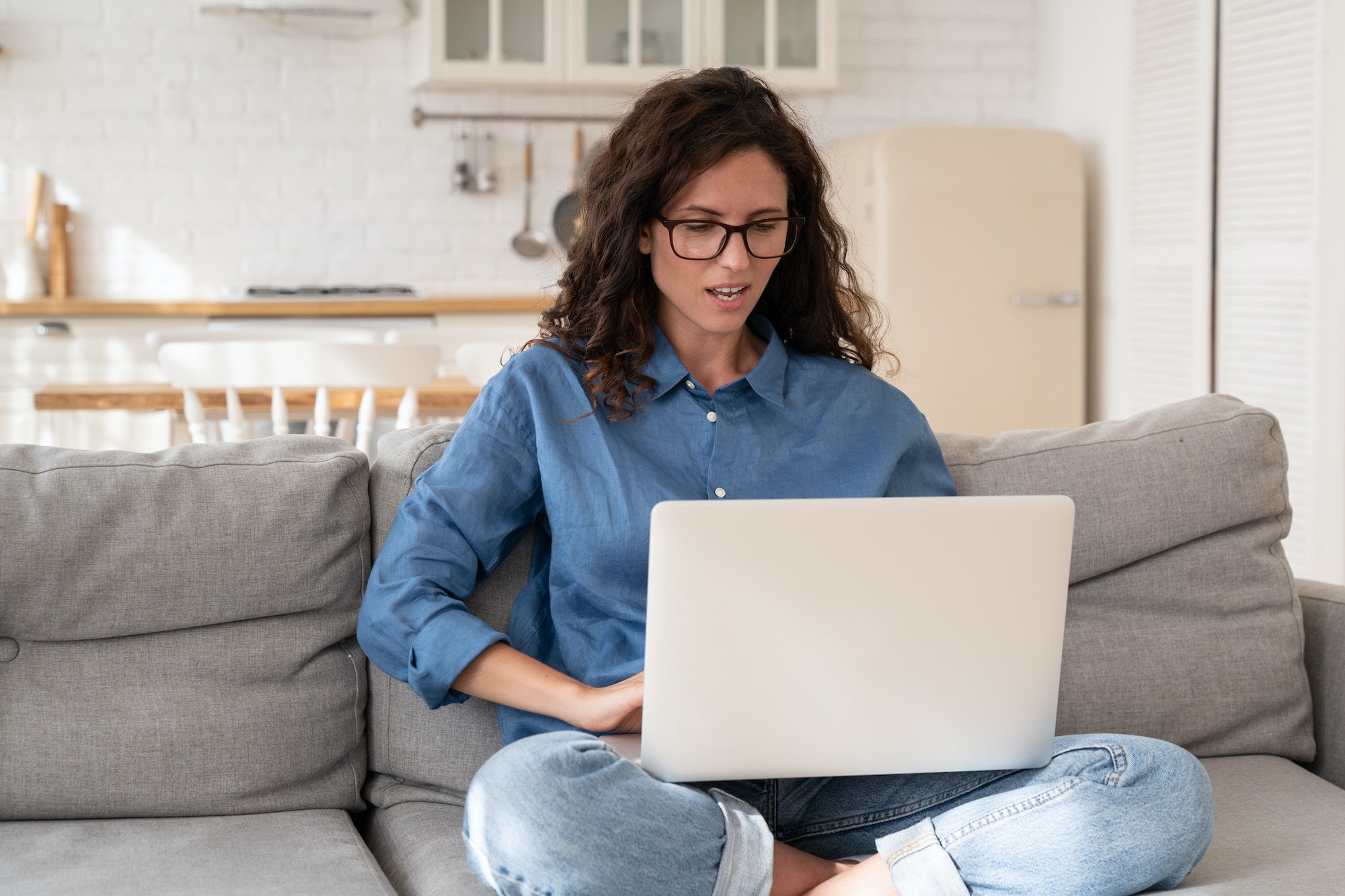 Frustrated woman look on laptop screen with open mouth and distrust on face sitting on sofa at home