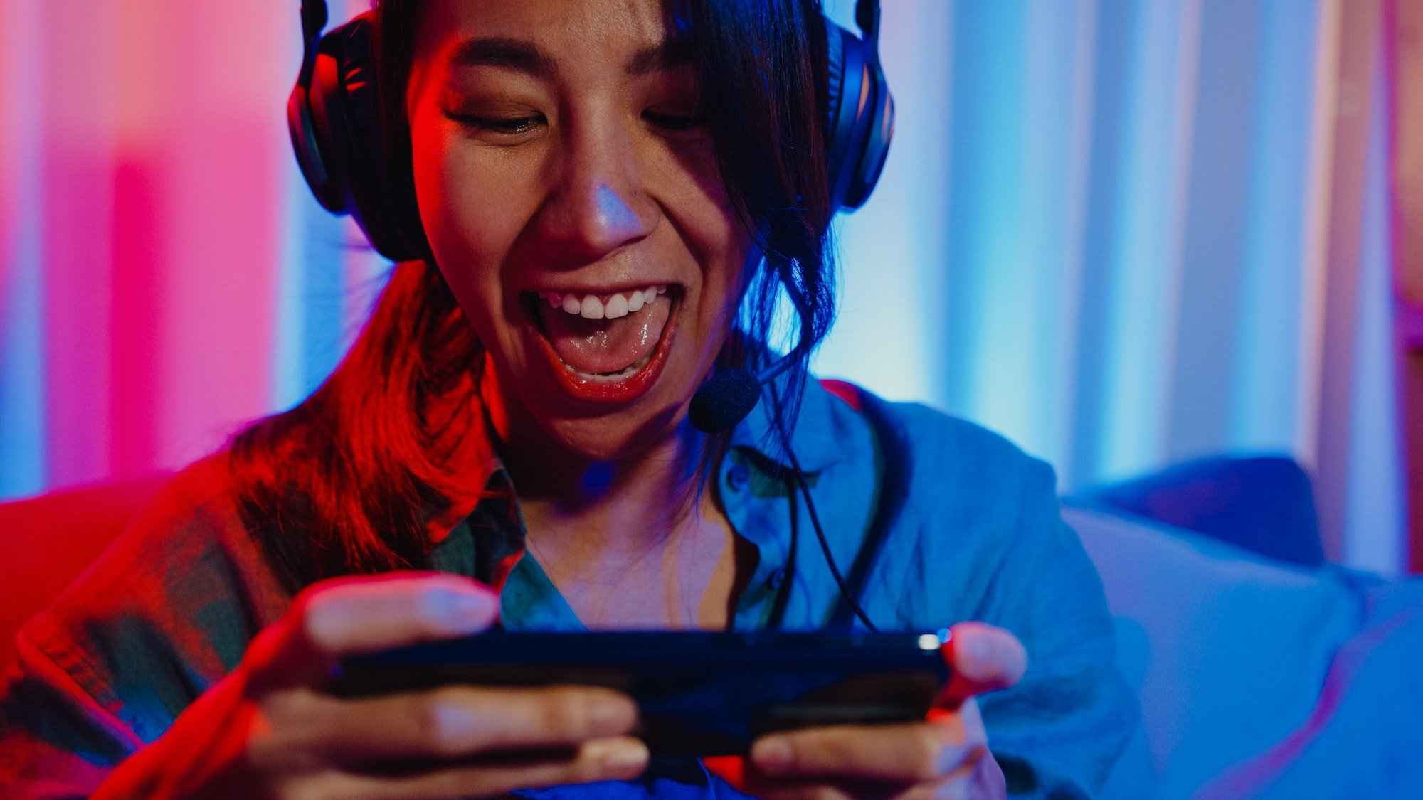 asia girl gamer wear headphone competition video game online with smartphone.